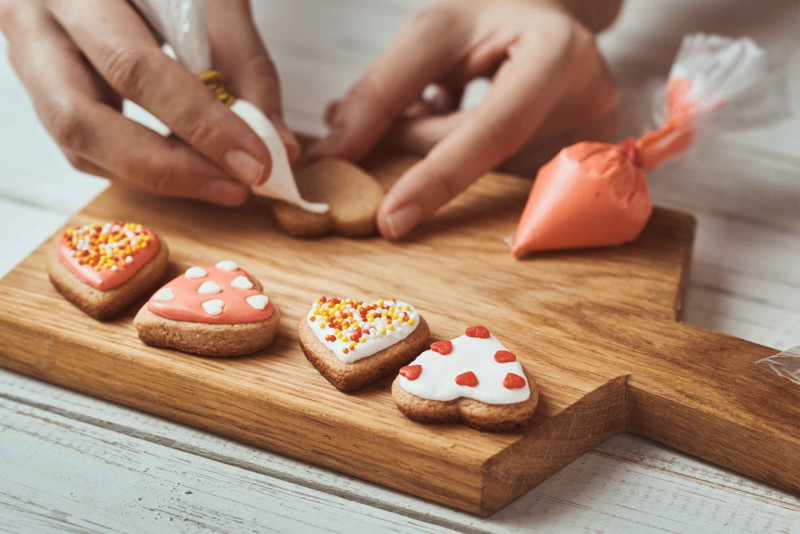 decorating-heart-shaped-cookies-with-icing-and-spr-20-10409460